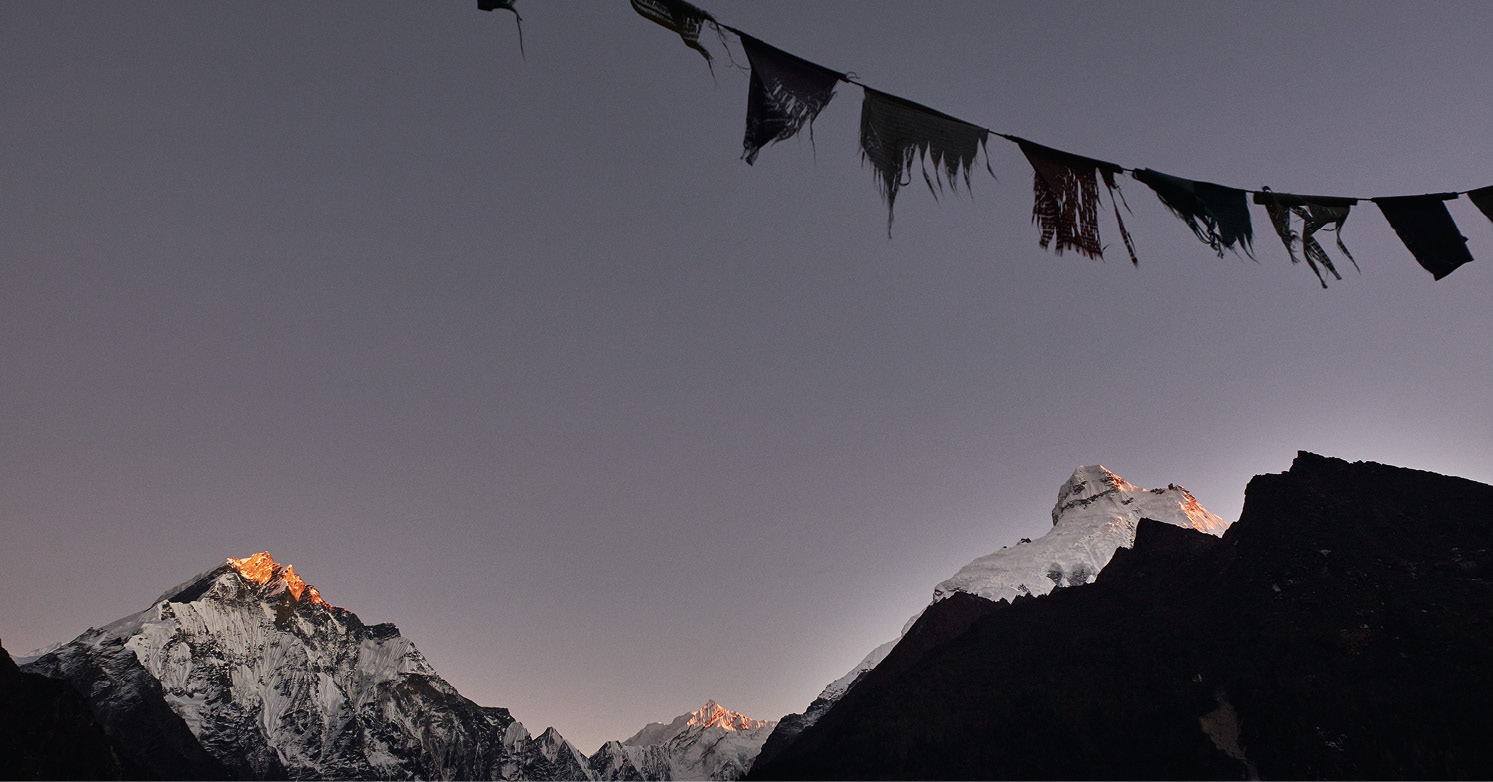 Berggipfel und Gebetsfahnen im Abendlicht: Himalaya-Glühen mit den Gipfeln der Ganesh-Gruppe