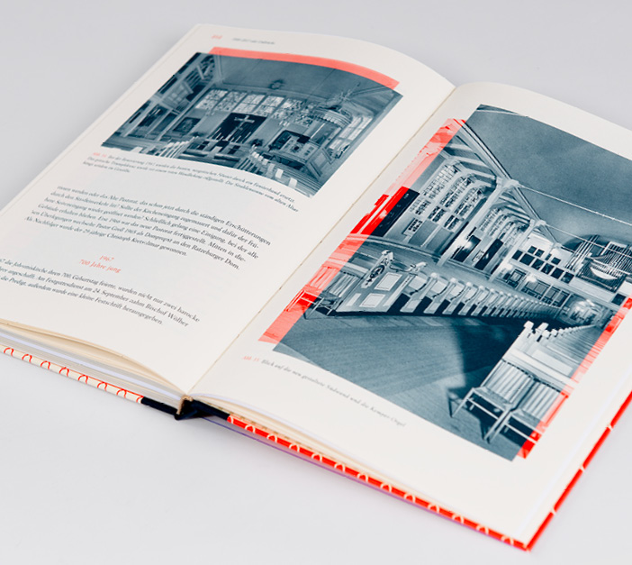 Aufgeschlagenes Buch. Auf der Doppelseite sind Text und Bilder in Schwarz-Weiß mit roten Gestaltungselementen.